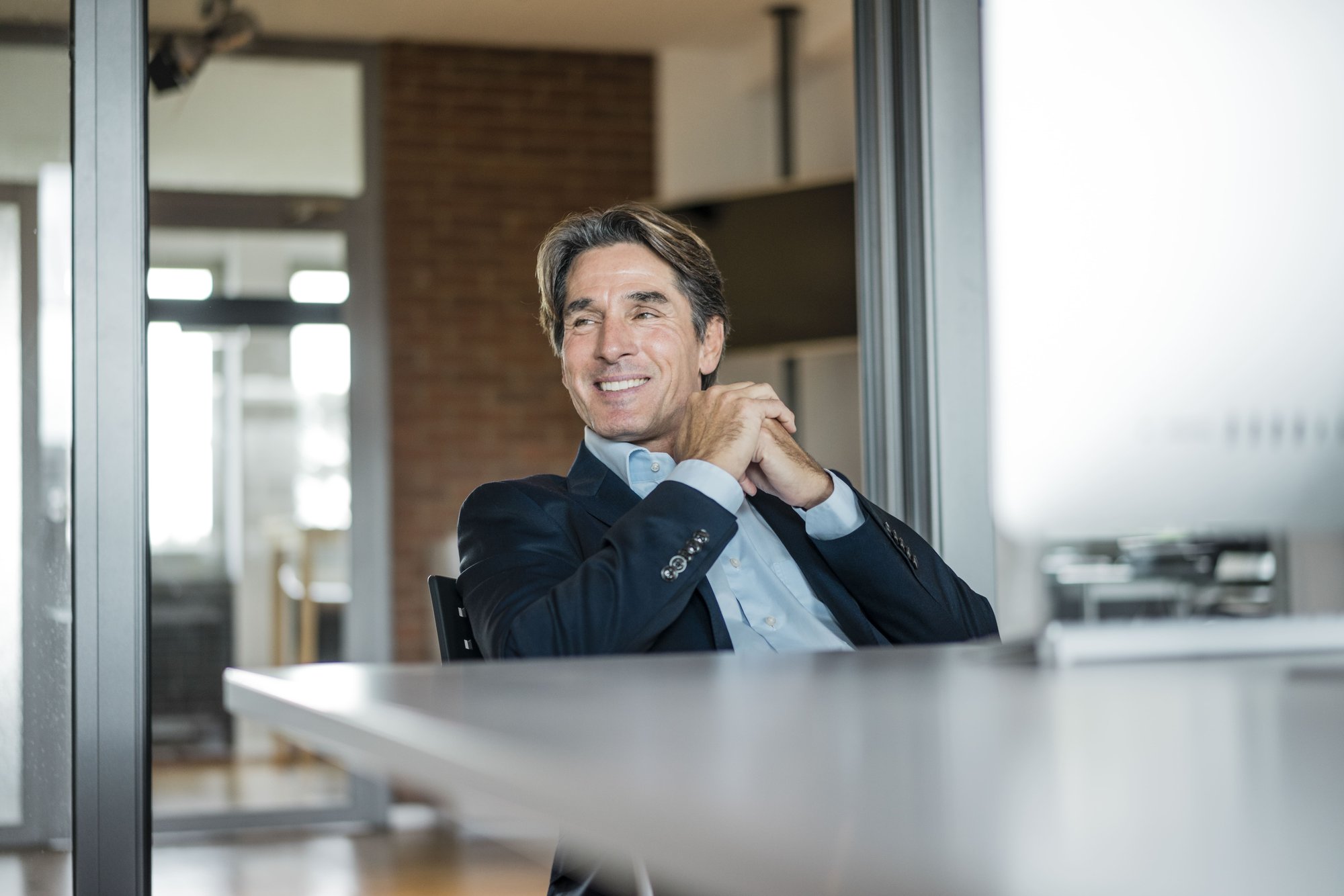 smiling-businessman-sitting-at-table-in-office-2026-01-05-00-41-12-utc